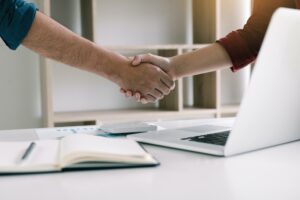 Co-worker startup shaking hands with colleagues in home office.